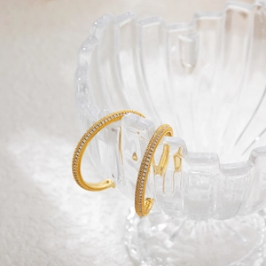 Macro shot of 18K gold plated hoop earrings with micro-pave cubic zirconia on glass