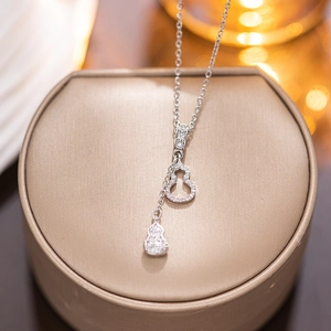 Elegant silver calabash pendant necklace with micro-paved diamonds on a jewelry box
