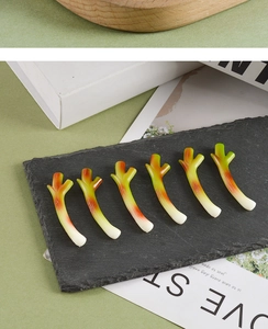 Detailed set of six miniature green onion food models on a textured slate background