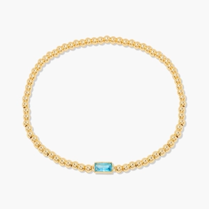 Bracelet minimaliste en perles dorées orné d'une pierre précieuse bleue rectangulaire de décembre