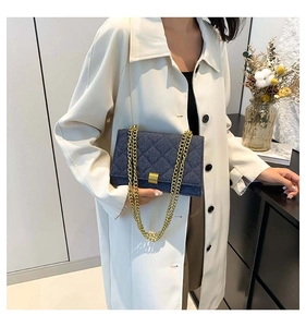 Detail of blue denim crossbody bag with quilted diamond pattern and gold chain strap