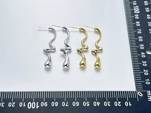 Dettaglio di orecchini a onde in oro e argento con scala di misurazione lineare