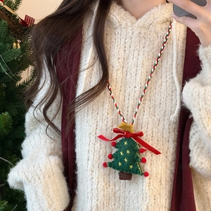 Detail of green plush Christmas tree necklace with red bow and woven cord on a model
