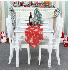 Close-up of a red Christmas table runner with white snowflake and tree prints on white table