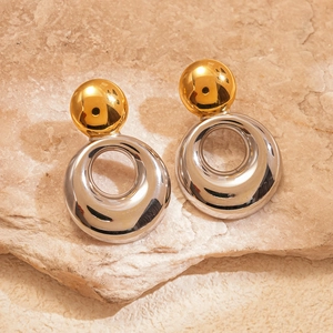 Détail de boucles d'oreilles bicolores géométriques avec clous dorés et anneaux argentés