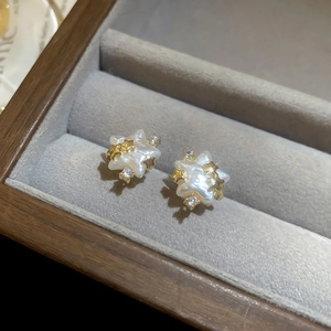 Gros plan sur les boucles d'oreilles étoile dorées 14 carats en nacre et zircons cubiques