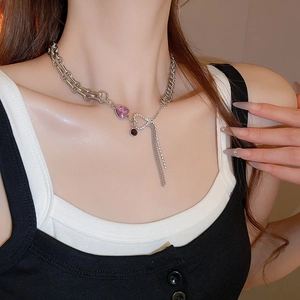 Silver chain necklace with pink heart pendant and tassels shown on a model neck