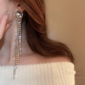 Detail of long tassel earrings with silver base and sparkling zircons on model