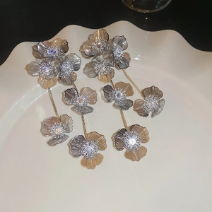 Détail de boucles d'oreilles fleurs argentées avec zircons sur une assiette blanche