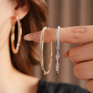 Dettaglio di orecchini a cerchio intrecciati in oro e argento con cristalli brillanti