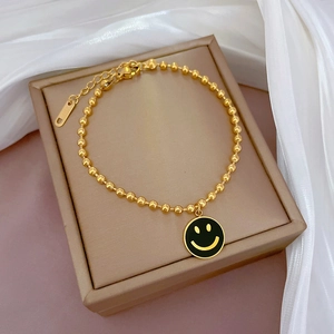 Makroansicht der goldenen Perlenarmband mit schwarzem Smiley-Anhänger auf Schmuckschachtel