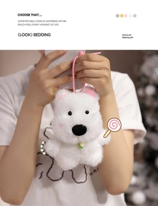 Detail of white plush puppy keychain with pink ears and a green-yellow bell accessory