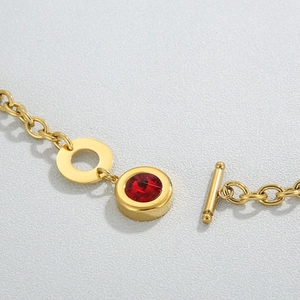 Macro view of gold stainless steel thick chain necklace with red gemstone and OT buckle