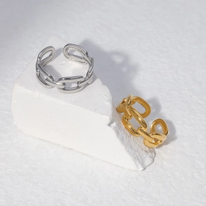 Close-up of gold and silver chain link rings on a white geometric stone pedestal
