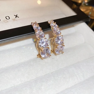 Macro shot of elegant gold flower earrings with four clear cubic zirconia stones