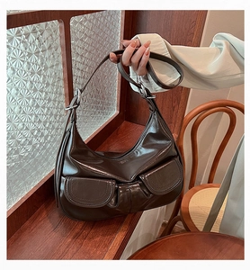 Close-up of a vintage dark brown patent leather hobo bag with dual front pockets and silver hardware