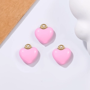Detailed view of pink heart-shaped charms with golden metal loops for jewelry making