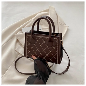 Detailed close-up of dark brown quilted leather square bag with heart stitching detail