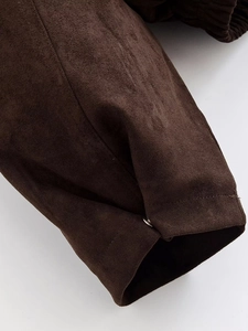 Detail of dark brown faux suede fabric with precise stitching and a metal fastener