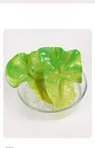 Realistisches künstliches Salatblatt mit Wassertropfen in Glasschale auf weißem Hintergrund