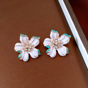 Detail of flower earrings with white enamel petals, turquoise beads and crystal center