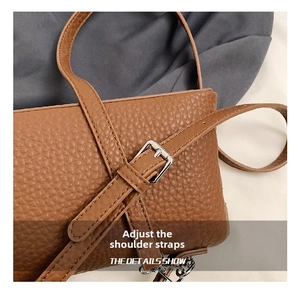 Detail of adjustable shoulder strap with silver buckle on brown lychee pattern bag