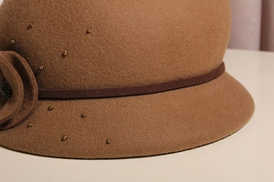 Dettaglio cappello cloche in lana con fiore fatto a mano e delicate perle dorate