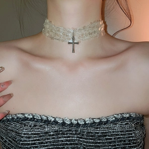 Gros plan d'un choker en dentelle vintage avec pendentif croix argenté et paillettes