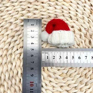 Mini bonnet de Noël tricoté rouge et blanc avec règle montrant une hauteur de 6cm et largeur de 4,5cm