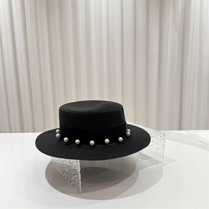 Détail d'un chapeau de paille noir avec ruban de soie orné de perles sur présentoir