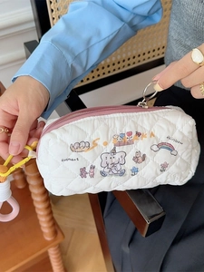 Quilted white pencil case with cute cartoon prints and pink zipper held by a hand