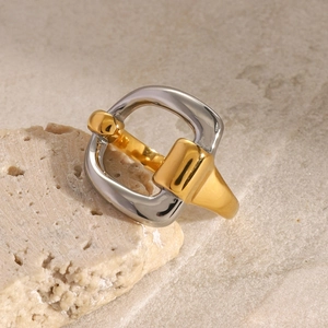Detailed view of two-tone gold and silver interlocking buckle ring on a stone surface