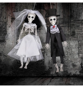 Hanging skeleton bride and groom dolls in wedding attire against a bloody haunted wall