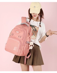Pink waterproof nylon backpack with bear keychain accessory shown on a model