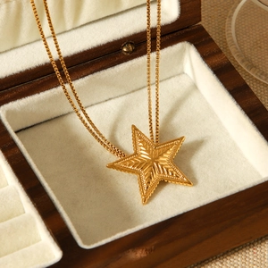 Detail of a golden star pendant necklace resting in a premium wooden jewelry box