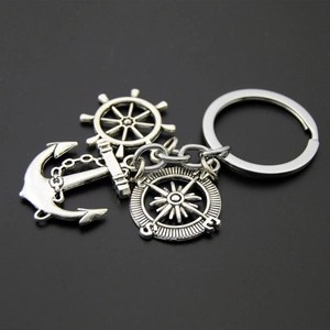 Macro view of vintage silver nautical keychain with anchor, rudder, and compass charms