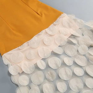 Detail of yellow fabric and pink 3D floral organza mesh on the tiered dress skirt