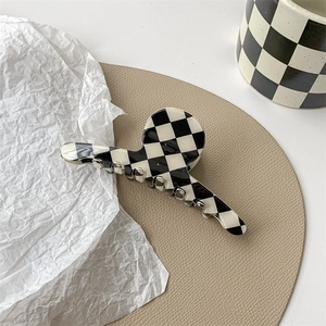 Detailed view of large black and white checkerboard hair claw clip with glossy resin finish