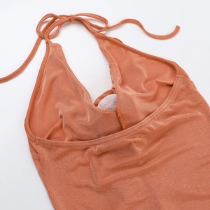 Close-up of orange halter neck dress showing ruched chest detail and shimmering fabric