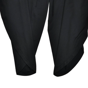 Close-up of the gathered hem detail and ruched split hem on a black long sleeve jumpsuit