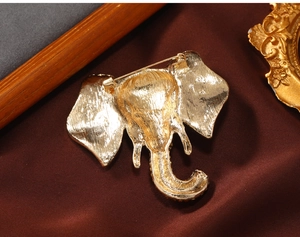 Detail view of gold elephant brooch back showing pin structure on silk fabric