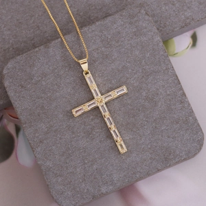Macro detail of 18K gold plated cross pendant with rectangular cubic zirconia on box chain