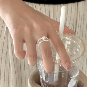 Detail shot of a beaded silver ring with a lustrous white pearl on a model's finger