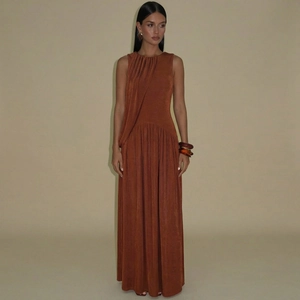 Detailed view of the sleeveless maxi dress featuring a ruched waist and glossy fabric texture