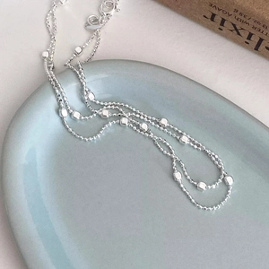 Dettaglio macro della collana a catena con cubi in argento S925 su piatto in ceramica