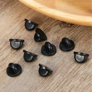 Macro view of black PVC rubber pin backs scattered on a rustic wooden texture background