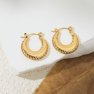Macro detail of 18K gold plated hoop earrings with serrated edges on a stone base