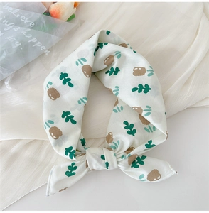 Detail of a white cotton linen scarf with brown animal and green plant prints tied in a knot