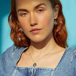 Close-up of Bohemian sun relief pendant necklace and earrings on model with blue denim