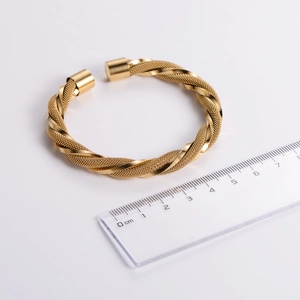 Detailed macro view of gold-plated stainless steel twisted mesh open bangle with textured surface